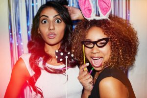 Shot of two beautiful young women having fun with props in a photobooth